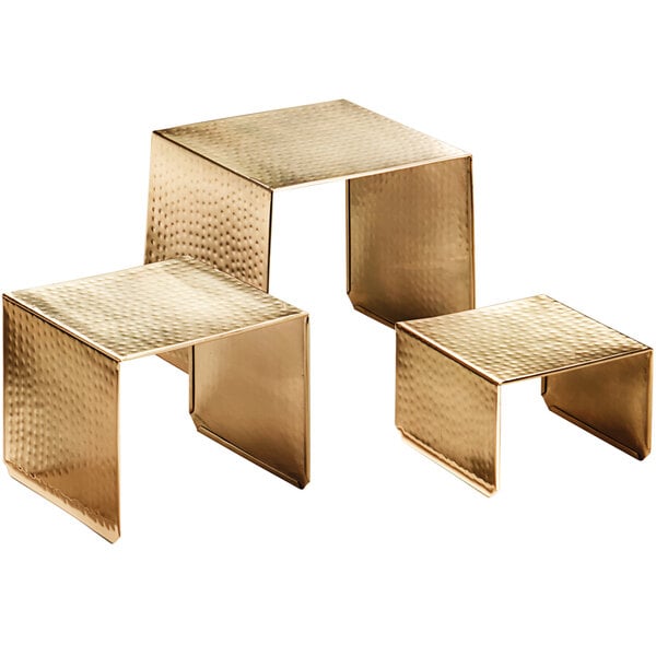 Three gold metal American Metalcraft display risers with a hammered finish.