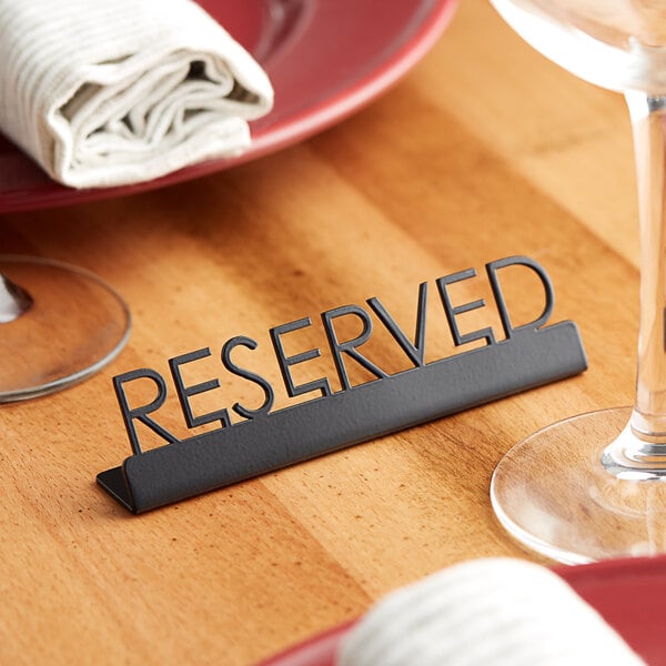A black American Metalcraft tabletop reserved sign on a table.