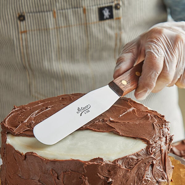 A person using an Ateco straight blade spatula to spread icing on a cake.