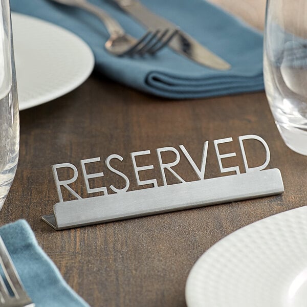 A table set with a reserved sign in a stainless steel holder.