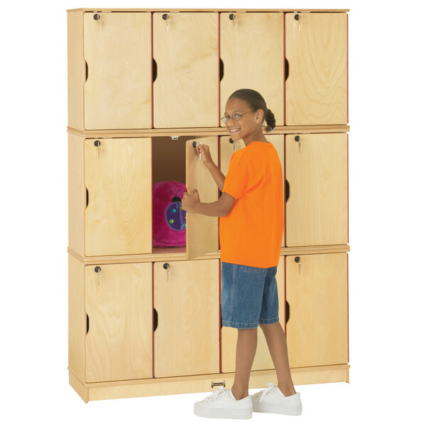 A girl standing next to a Jonti-Craft triple stack wooden locker.
