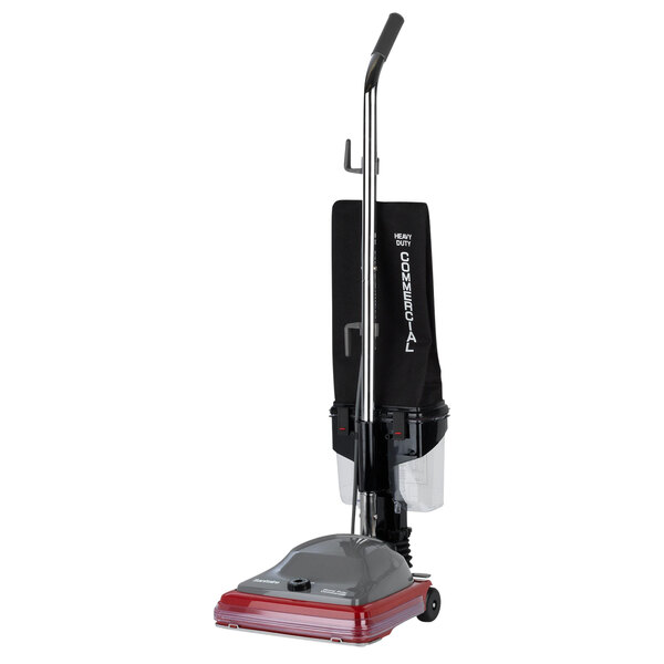 A Sanitaire upright vacuum cleaner with a red handle and black wheels.