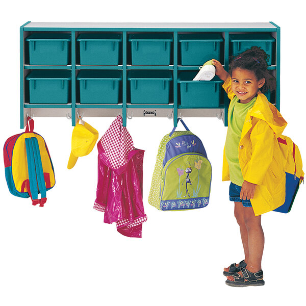 A little girl standing next to a Rainbow Accents teal and gray coat rack with teal trays and double hooks.