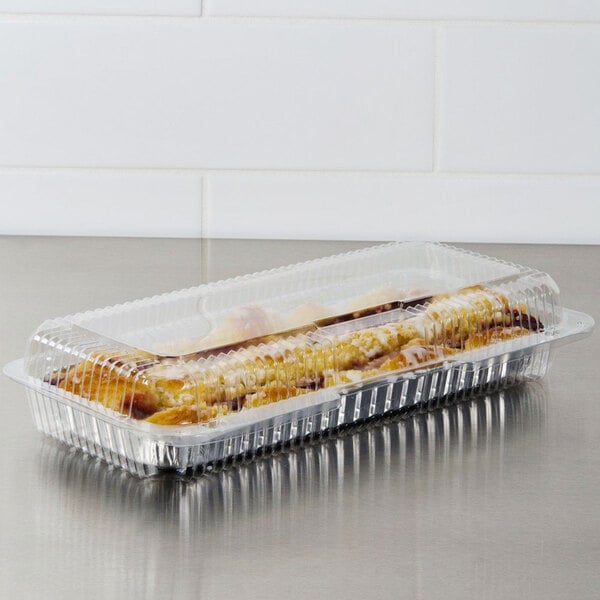 A Dart clear hinged plastic strudel container on a counter with strudel inside.