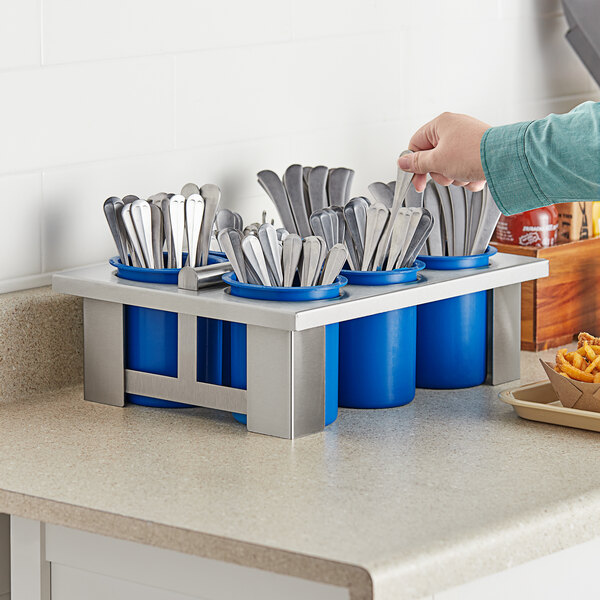 A person holding a blue Steril-Sil flatware container filled with utensils.