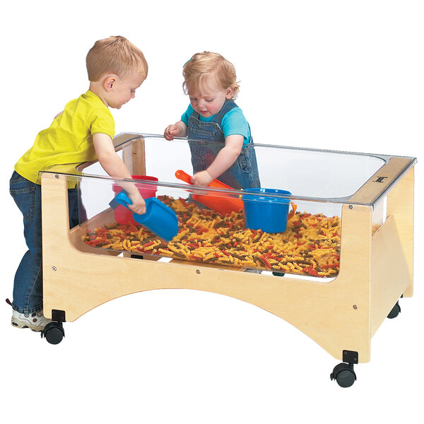 A couple of children playing in a Jonti-Craft mobile wood sensory table with a blue scoop.