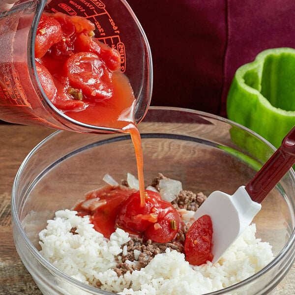 A bowl of rice with Furmano's stewed tomatoes being poured from a measuring cup.