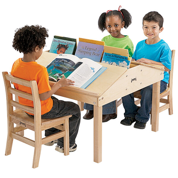 Three children sitting at a Jonti-Craft children's reading table with books.