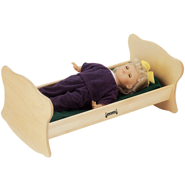 A doll lying in a Jonti-Craft wooden bed.