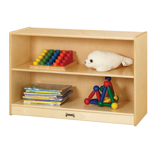 A Jonti-Craft natural wood short bookcase with toys and a stuffed animal on the shelves.
