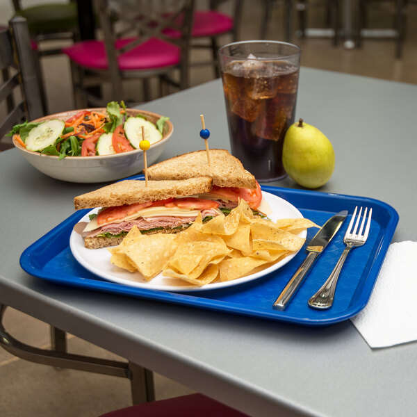 A Carlisle blue plastic fast food tray holding a sandwich, salad, and chips.