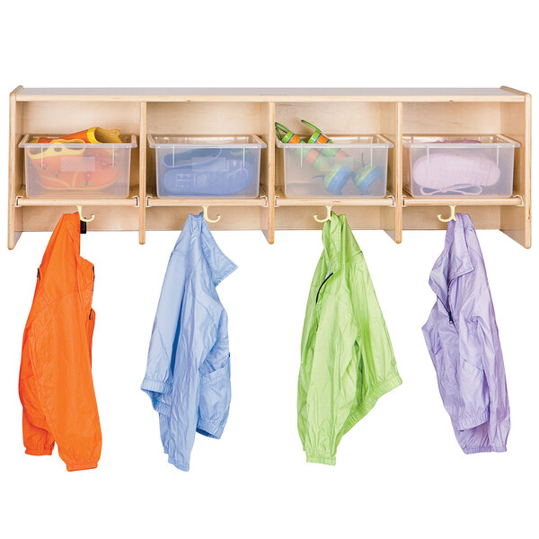 A Jonti-Craft wooden coat locker with plastic bins and three colored jackets hanging.