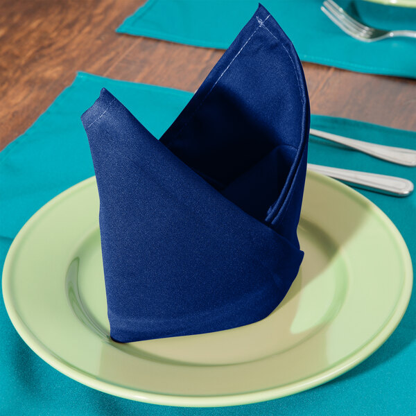 A folded royal blue Intedge cloth napkin on a plate.