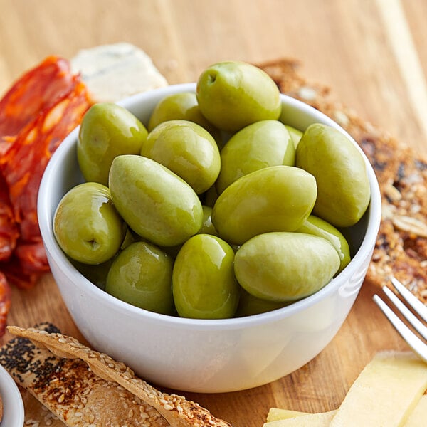 A bowl of Frutto d'Italia Green Cerignola Olives on a wooden table.