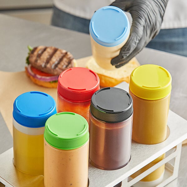 A person putting condiments in a plastic squeeze bottle with a Tablecraft 63FCAPA end cap.
