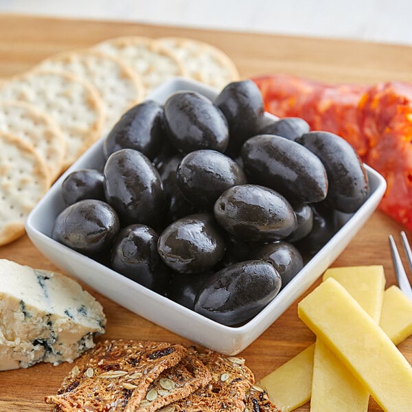 A bowl of Frutto d'Italia black Cerignola olives on a wooden surface.