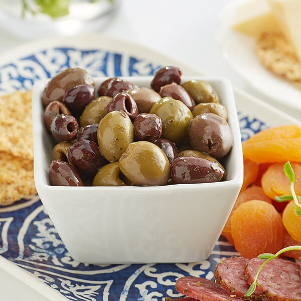 A bowl of Frutto d'Italia Pitted Mediterranean Olive Mix on a table with cheese and crackers.