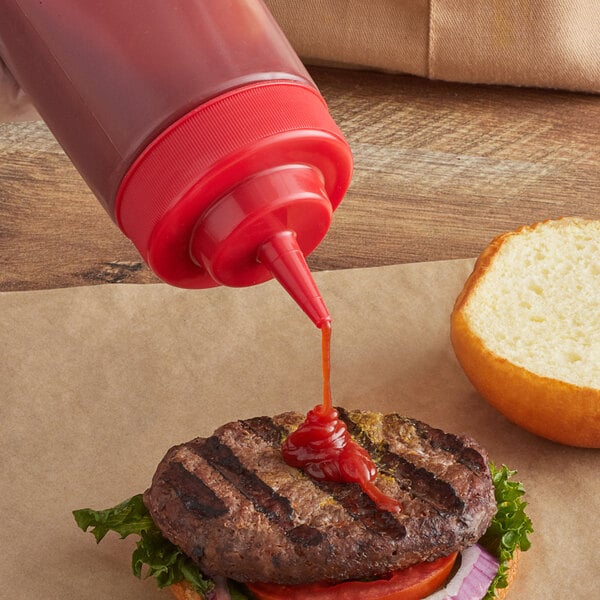 A Tablecraft red squeeze bottle cap pouring ketchup on a burger.