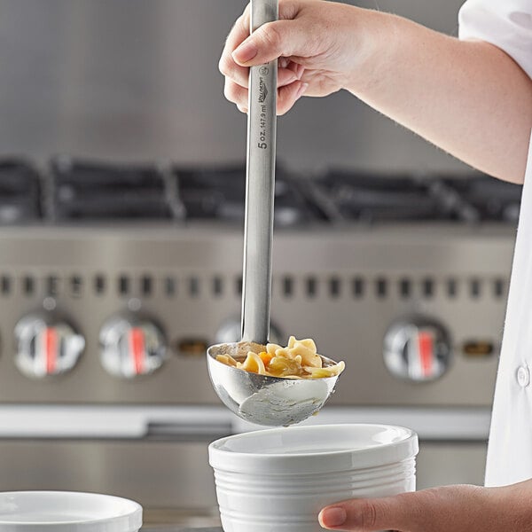 A person using a Vollrath stainless steel ladle to serve food.