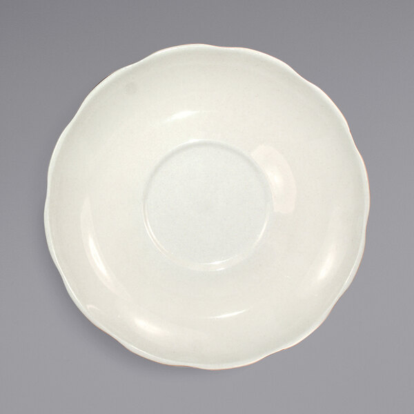 An International Tableware Victoria ivory saucer with a scalloped edge.
