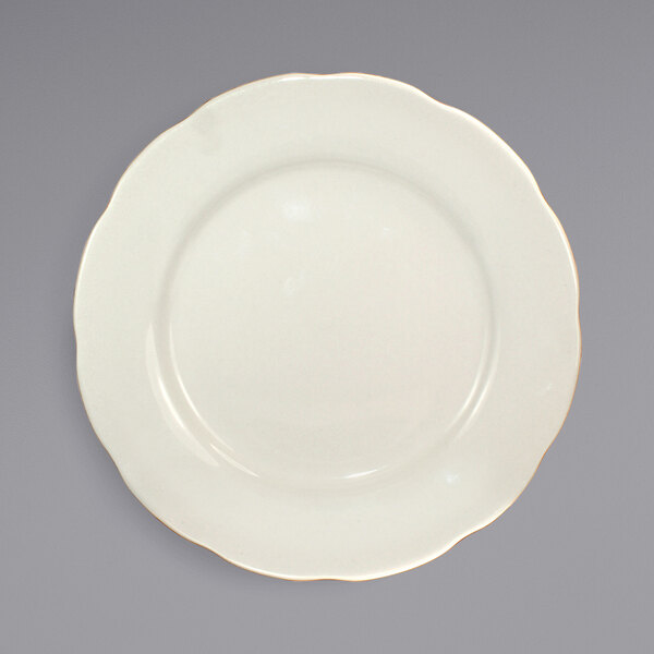 An International Tableware Victoria ivory stoneware plate with a scalloped edge and gold trim.