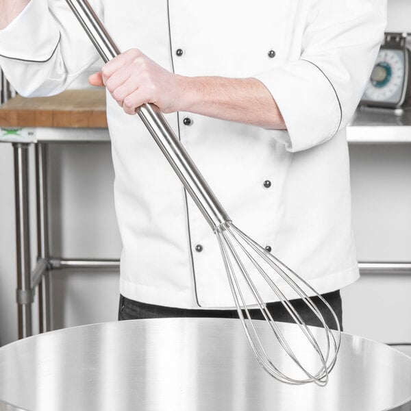 A person using a Thunder Group stainless steel piano whisk in a large silver pot.