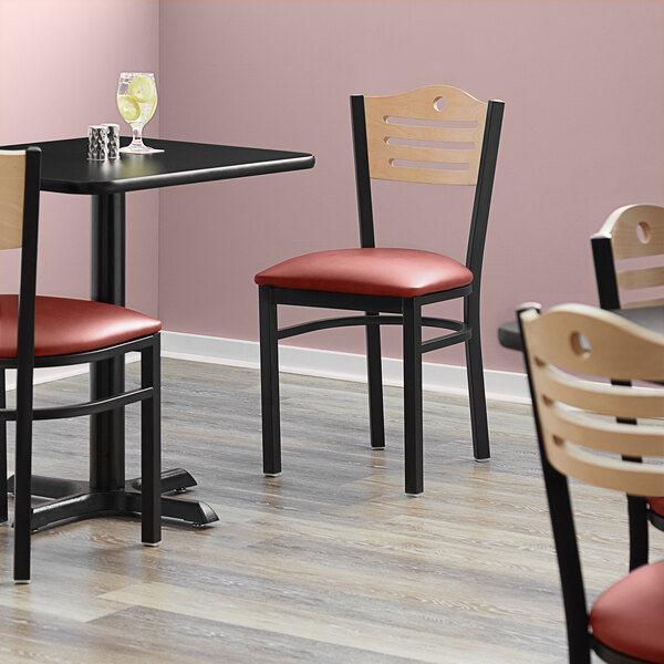 A Lancaster Table & Seating black bistro chair with a burgundy seat in a room with tables and chairs.