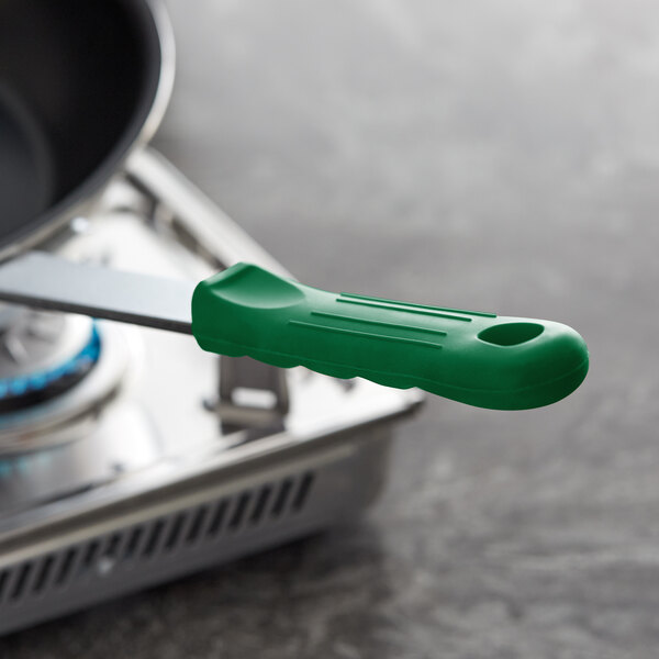 A green removable silicone sleeve on a pan handle.