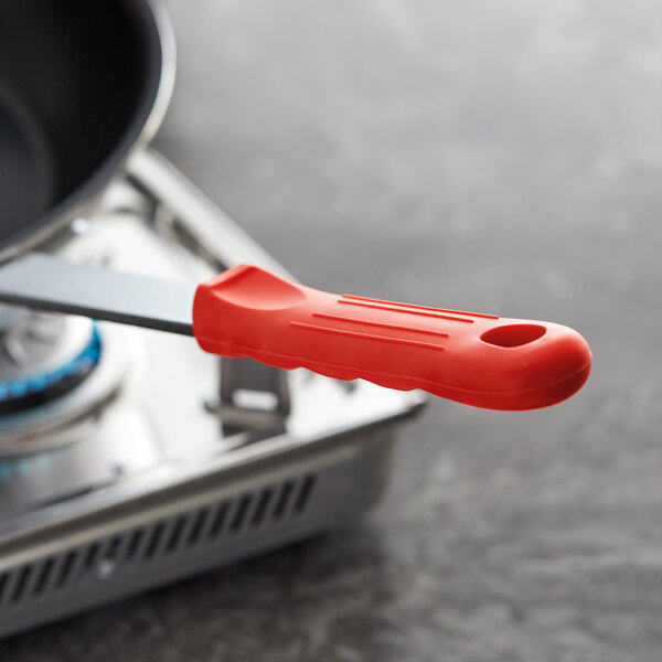 A pan with a red Choice silicone handle cover on the handle.