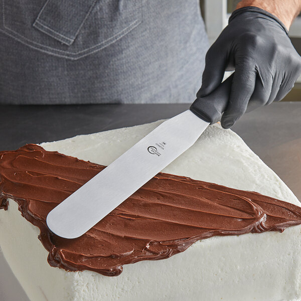 A person using a Mercer Culinary baking spatula to spread frosting on a cake.