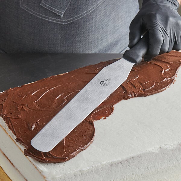 A person using a Mercer Culinary straight baking spatula on a cake.