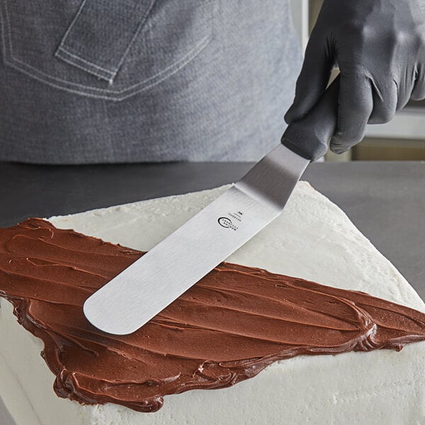 A person using a Mercer Culinary offset spatula to frost a cake.