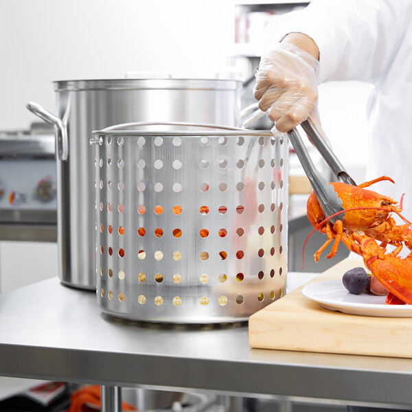 A person using a Vollrath fryer basket to cook a lobster.