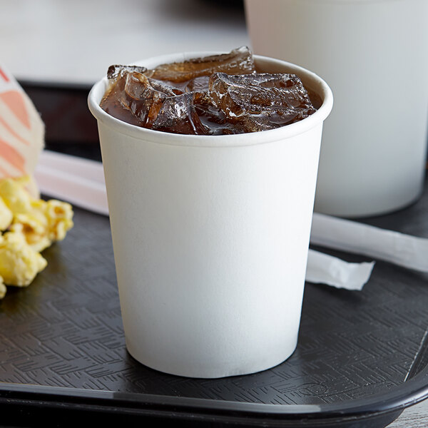 A tray with a cup of soda with ice and popcorn on it with a Choice white poly paper cold cup filled with ice and soda.