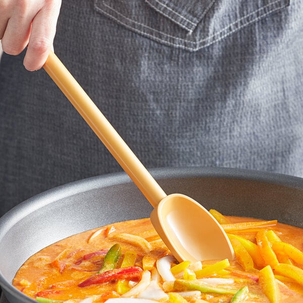 A person stirring a pot of food with a tan Mercer Culinary high temperature mixing spoon.