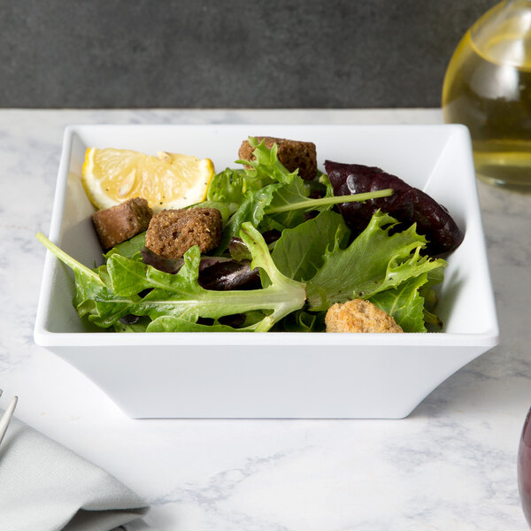 A white Siciliano square bowl filled with salad and a lemon slice.