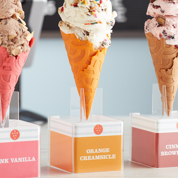 A Konery waffle cone stand holding three ice cream cones with a pink one in the middle.