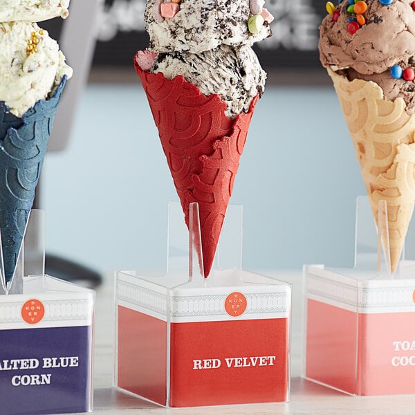 A Konery waffle cone stand holding three red velvet waffle cones.