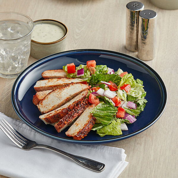An Acopa Azora Blue stoneware coupe plate with chicken salad and a fork.