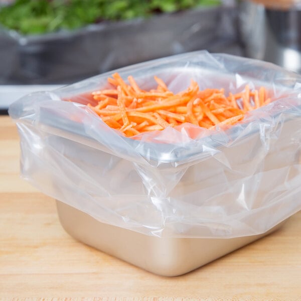 A plastic container filled with carrots in a 1/6 size nylon pan liner.