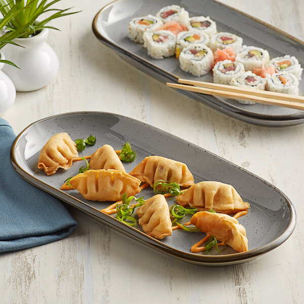 An Acopa Keystone granite gray stoneware oblong coupe platter with sushi and chopsticks on it.