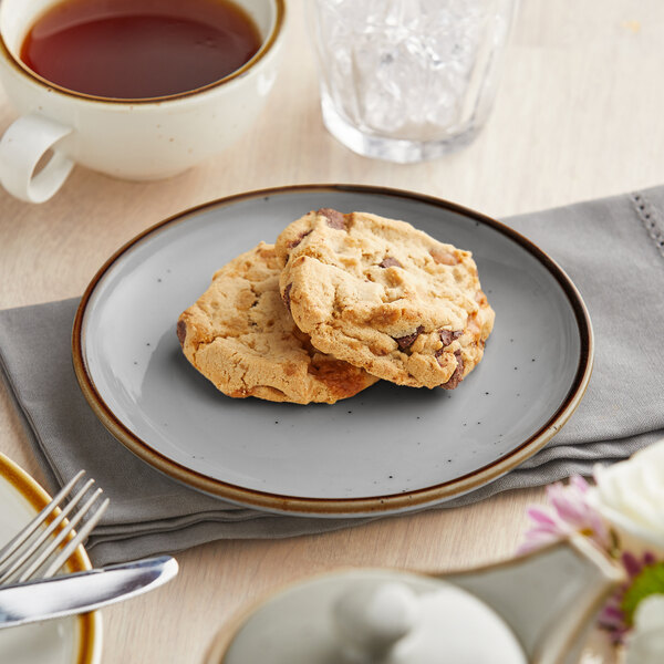 A granite gray Acopa stoneware coupe plate with cookies and tea on it on a table.