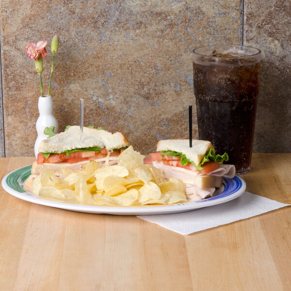 A white oval melamine platter with sandwiches and chips.