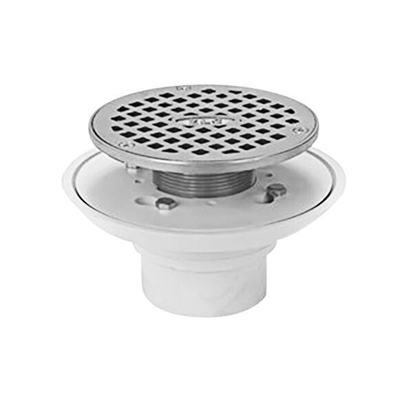 A Zurn 2" PVC shower drain with a metal cover over a white drain hole.