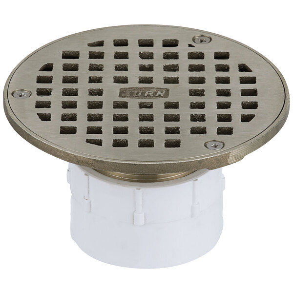 A Zurn round metal floor drain with a white plastic base.