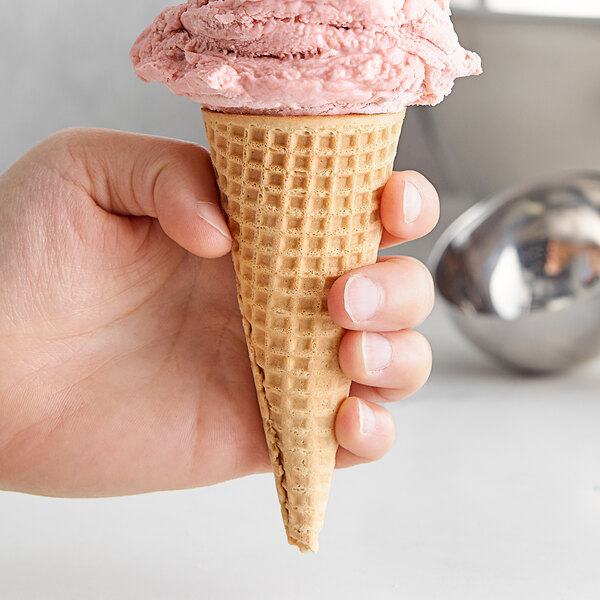 A hand holding a Keebler Honey-Roll sugar cone filled with pink ice cream.