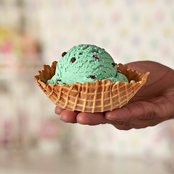 A hand holding a Keebler Waffle Bowl with green ice cream.