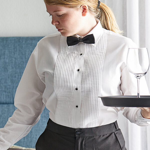 A woman in a Henry Segal white tuxedo shirt with a bow tie holding a tray with a wine glass.