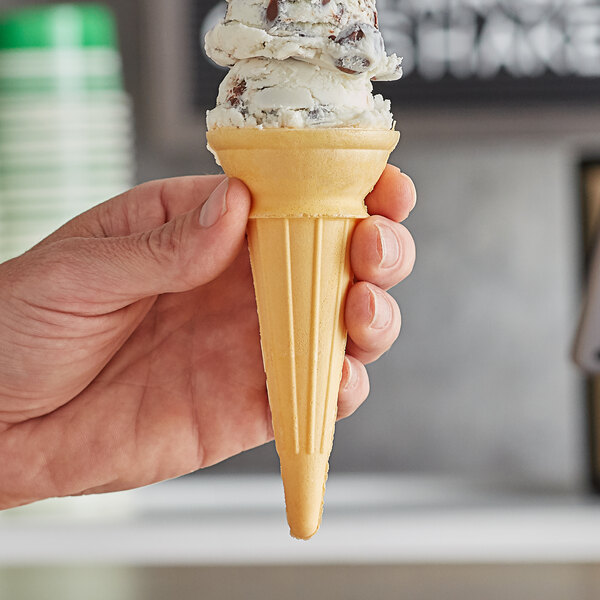 A hand holding a Keebler Eat-It-All ice cream cone filled with chocolate chip ice cream.