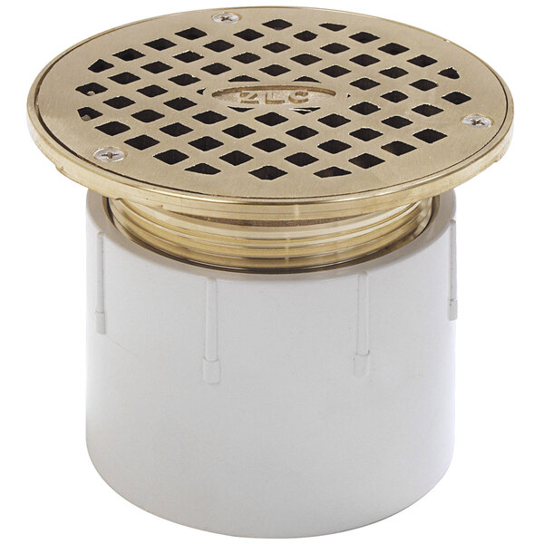 A white plastic Zurn floor drain with a gold metal cover.